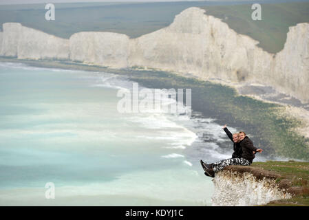 Touristen ihre Leben riskieren für selfies auf die bröckelnden Kreidefelsen am Birling Gap, in der Nähe der berühmten Sieben Schwestern, East Sussex. Stockfoto