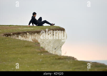 Touristen ihre Leben riskieren für selfies auf die bröckelnden Kreidefelsen am Birling Gap, in der Nähe der berühmten Sieben Schwestern, East Sussex. Stockfoto