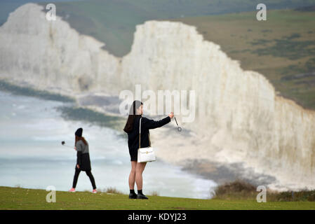 Touristen ihre Leben riskieren für selfies auf die bröckelnden Kreidefelsen am Birling Gap, in der Nähe der berühmten Sieben Schwestern, East Sussex. Stockfoto