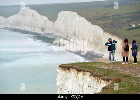 Touristen ihre Leben riskieren für selfies auf die bröckelnden Kreidefelsen am Birling Gap, in der Nähe der berühmten Sieben Schwestern, East Sussex. Stockfoto