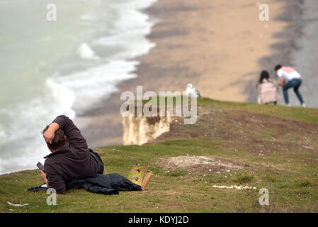 Touristen ihre Leben riskieren für selfies auf die bröckelnden Kreidefelsen am Birling Gap, in der Nähe der berühmten Sieben Schwestern, East Sussex. Stockfoto