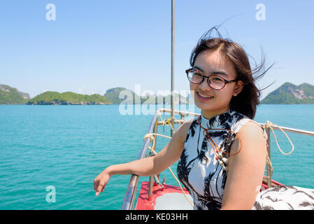 Nette junge Frau mit Brille glücklich lächelnd auf dem Bug Boot, während die schöne Natur der blauen Himmel und Meer Kreuzfahrt im Sommer an Mu Ko ang Stockfoto