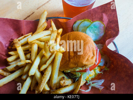 Hamburger und Pommes frites in einem Korb mit einem Plastikbecher Bier Stockfoto