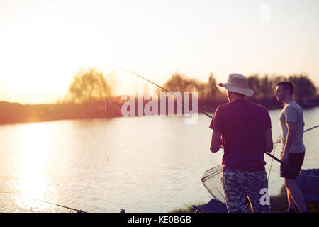 Männer angeln in den Sonnenuntergang und entspannen bei Hobby Stockfoto