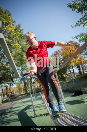 Bad Schönborn, Deutschland. Oktober 2017. Klaus Heinzmann, Teilnehmer einer Langzeitstudie zum Gesundheitsvergleich von sportlich aktiven und nicht sportlich aktiven Menschen, praktiziert in einem Aktivpark in Bad Schönborn, 16. Oktober 2017. Die Studie der Gemeinde Schönborn und des Karlsruher Instituts für Technologie (KIT) läuft seit 25 Jahren. Das Ergebnis: Sportlich aktive Menschen mittleren Alters verfügen über bessere motorische Fähigkeiten, die einen Unterschied zwischen 10 Jahren und Menschen machen, die nicht sportlich aktiv sind. Quelle: Sina Schuldt/dpa/Alamy Live News Stockfoto