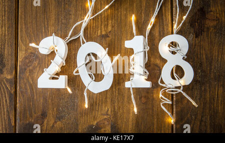 2018 Mit Weihnachtsbeleuchtung auf rustikalen hölzernen Hintergrund Stockfoto