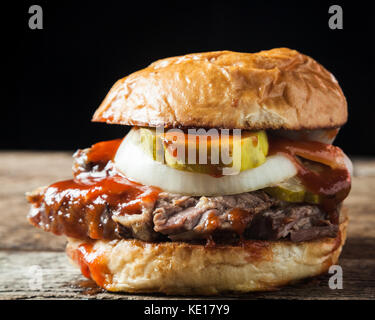 Geräucherter unterbrust Sandwich mit Gurken, Zwiebeln und BBQ-Soße auf rustikalen Hintergrund Stockfoto