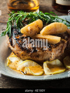 Schweinefleisch vom Grill mit Bourbon chop gewürzt Ahorn Äpfel mit Bratkartoffeln auf rustikalen Hintergrund serviert. Stockfoto