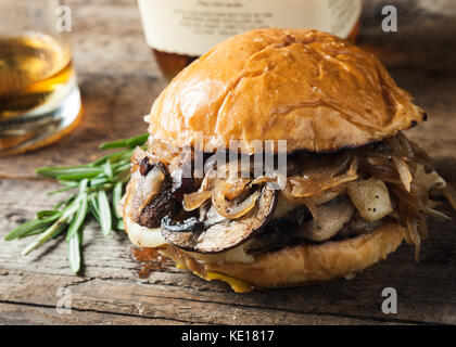 Burger mit Pilzen, gebratenen Zwiebeln und Käse auf rustikalen Hintergrund Stockfoto
