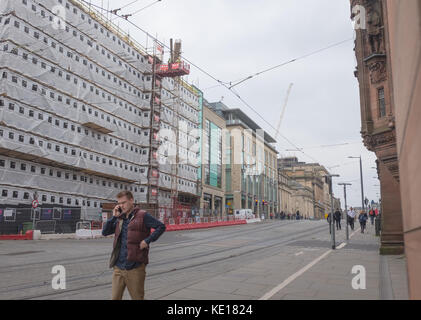 Mann, lässig gekleidet, läuft eine Straße in Edinburgh, Schottland, und spricht mit jemandem auf seinem Handy. Stockfoto