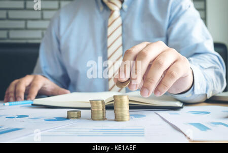 Nahaufnahme der Geschäftsmann Hand Münzen Münzen auf finanzielle Dokument zu Stapeln, Geschäftskonzept. Stockfoto