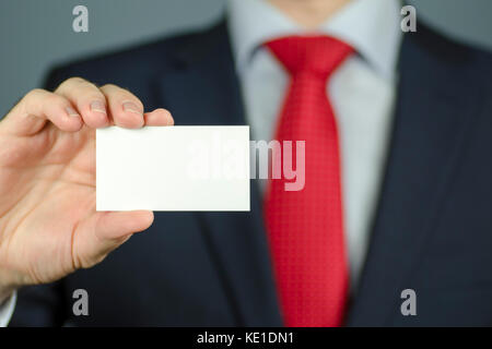 Nahaufnahme der Hand des Managers im Anzug und mit einer roten Krawatte Holding ein leeres weißes Visitenkarte Stockfoto