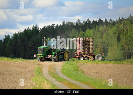 Salo, Finnland - 27. Mai 2016: John Deere 9520t Raupenschlepper und kultivator Verschieben entlang der Piste in ländlichen Frühling Landschaft auf dem Weg Stockfoto