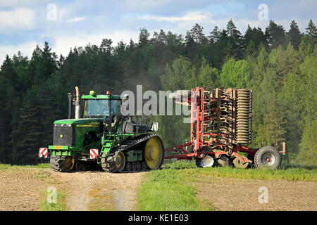 Salo, Finnland - 27. Mai 2016: John Deere 9520t Raupenschlepper und kultivator Verschieben entlang der Piste in ländlichen Frühling Landschaft auf dem Weg Stockfoto