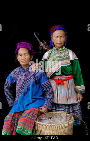 Sünde Cheng, Vietnam, 26. Oktober 2016: Frauen vor einem schwarzen Blatt. HMong Frauen im Norden Vietnams tragen ihre beste traditionelle Kleidung beim Gehen zu Stockfoto