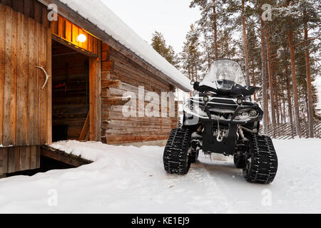 Quad Bike im Winter in der Nähe von Holz- häuser Stockfoto