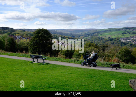 Hallam Moors, Peak District National Park, aus Bolehills, Crookes, Sheffield, Großbritannien - Mann auf einem Mobilitätsroller mit Hund, der vorbeifährt Stockfoto