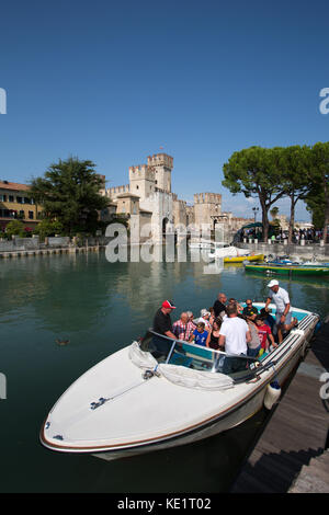 Sirmione, Italien. malerischen Blick auf eine touristische Bootsfahrt in den Burggraben der Scaliger Burg. Stockfoto