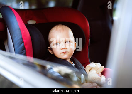 Süße kleine Baby boy in den Autositz sitzen im Auto, raus suchen. Bis zu schließen. Stockfoto