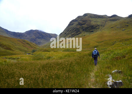 Hillwalker Fuß in Richtung der Corbett meall lighiche in gleann - leac-na-muidhe mit der munro sgor na h-ulaidh in der Ferne, die schottischen Highlands. Stockfoto