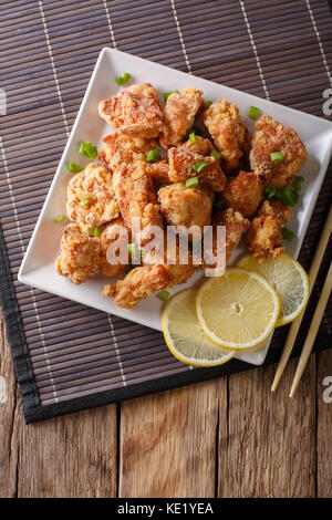 Teil gebratenes Huhn mit Zitrone und Zwiebel karaage Close-up auf einem Teller auf den Tisch. Senkrechte Draufsicht von oben Stockfoto