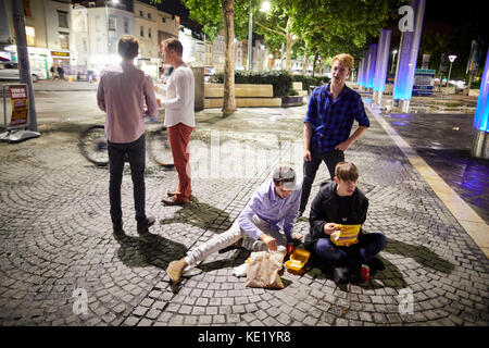 Bis spät in die Nacht getrunken revelers, Essen zum Mitnehmen, sitzen auf dem Boden in der Nähe der Anker auf der Watherfront in Bristol. Stockfoto