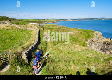 Ramblers auf Anglesey Coastal Path zu Fuß in Richtung Bucht von Lligwy Moelfre, Isle of Anglesey, North Wales, UK, Großbritannien Stockfoto