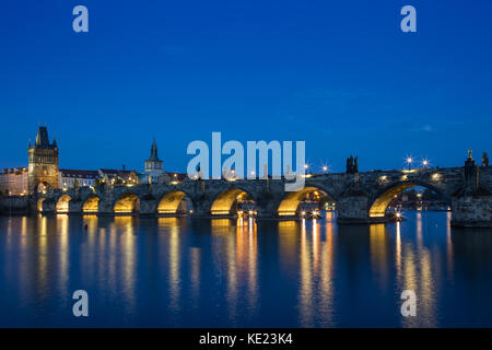 Leuchtet die Karlsbrücke (Karluv most) und alten Gebäuden in der Altstadt und deren Reflexionen an der Moldau in Prag, Tschechische Republik, in der Dämmerung. Stockfoto