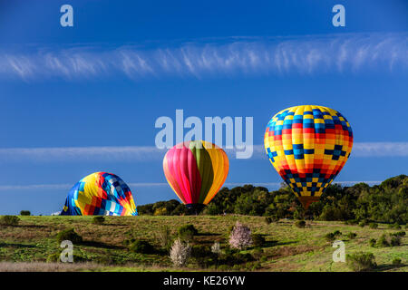 Heißluftballons Landung in einem offenen Feld unter einem klaren blauen Himmel in Napa, Kalifornien. Stockfoto