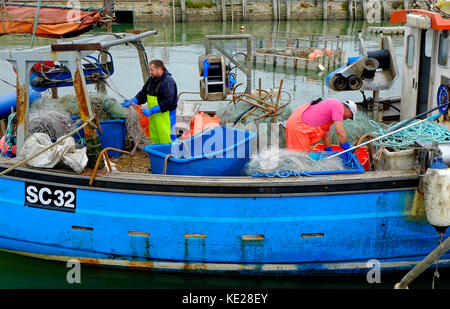 Fischer arbeiten auf Fischerboot deck, West Bay, Dorset, England Stockfoto