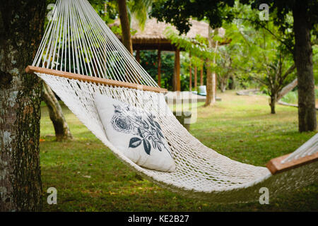 Leere weiße Hängematte mit Kissen hängen zwischen den Bäumen in einem schattigen Garten, Tangalle, Sri Lanka. Stockfoto