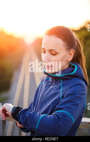 Portrait von jungen sportlichen Frau Kontrolle der Herzfrequenz auf Fitness Watch. athletischen stehendes Mädchen outdoor nach dem fitness training Stockfoto