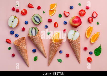 Bunte Eis mit gemischten Beeren und verschiedene Früchte Himbeere, Heidelbeere, Erdbeere, Orange Slice, Kiwi, Apfel, Zitrone und Pfefferminze auf Rosa backgr Stockfoto