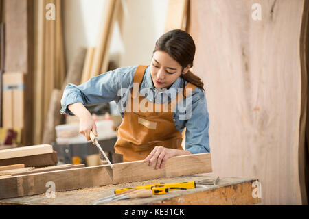 Junge weibliche Schreiner auf ihre Arbeit konzentrieren. Stockfoto