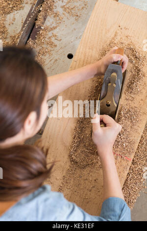 Zurück Portrait von jungen weiblichen woodworker auf ihre Arbeit konzentrieren. Stockfoto