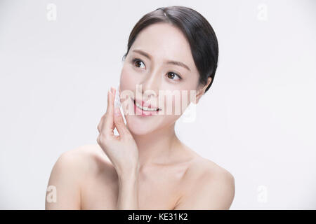 Portrait der junge lächelnde Frau ihr Gesicht Abwischen mit einem Wattepad Stockfoto