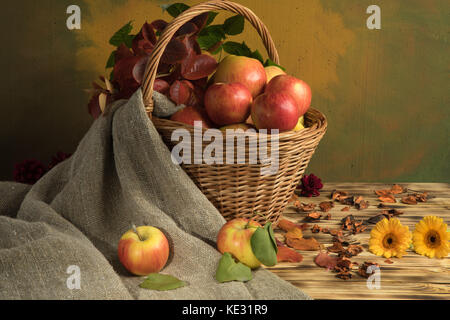 Äpfel in einem Korb mit Herbstlaub und Sackleinen Stockfoto