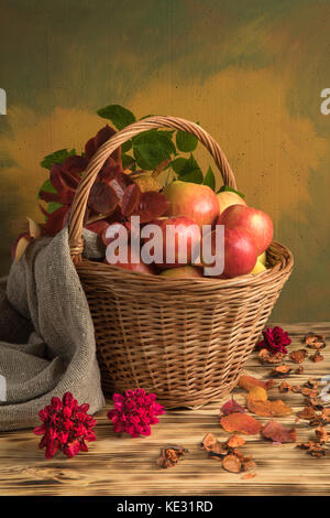 Äpfel in einem Korb mit Herbstlaub und Sackleinen Stockfoto