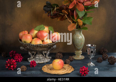 Äpfel in eine Vase mit Herbstlaub und Apfelsaft auf einem Tisch Stockfoto