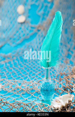 Blau Straußenfedern in Glas Flasche auf Fischnetz Hintergrund Stockfoto