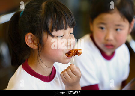 Japanische Grundschulkinder essen im Klassenzimmer Stockfoto