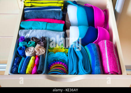 Akkurat gefaltete Kleidung mit Zubehör in Kommode Stockfoto