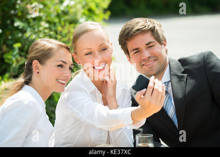 Junge glücklich männlichen und weiblichen Geschäftsleuten unter selfie mit Handy Stockfoto