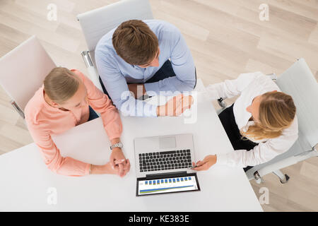 Hohe Betrachtungswinkel von Finanzberatern Händeschütteln mit Paar im Büro Stockfoto