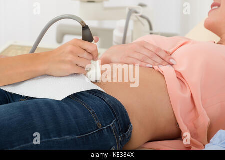 Nahaufnahme des Arztes bewegen Ultraschallsonde auf Bauch der schwangeren Frau im Krankenhaus Stockfoto