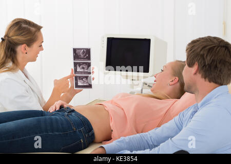 Ärztin mit Ultraschall für schwangere Frau und ihr Mann Stockfoto