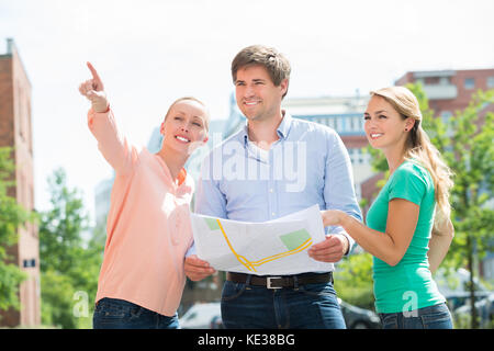 Gruppe von Lächelnden jungen Freunde Holding Karte auf der Suche nach Richtung Stockfoto