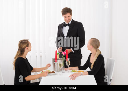 Kellner eine Bestellung von Glücklichen weibliche Freunde im Restaurant Stockfoto