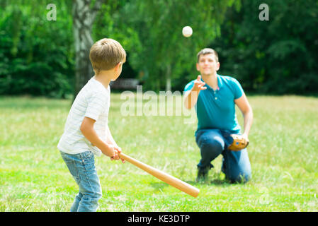 Wenig Junge spielt Baseball mit seinem Vater im Park Stockfoto