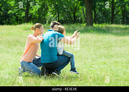Frau an ihrem Mann und ihrem Sohn nach Blick auf etwas Im Park Stockfoto